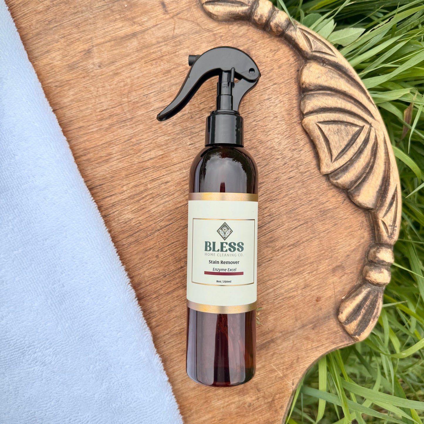 Brown spray bottle with 'Bless' label on a wooden horse head sculpture with grass in the background