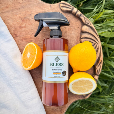 Bless surface spray bottle with lemons and oranges on a wooden board outdoors