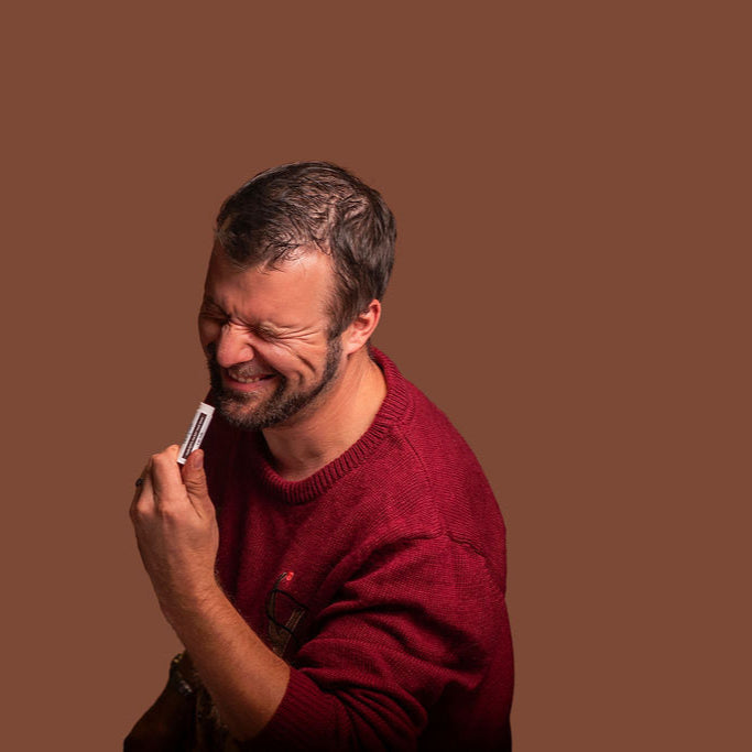Man in a red sweater holding a smartphone against a brown background