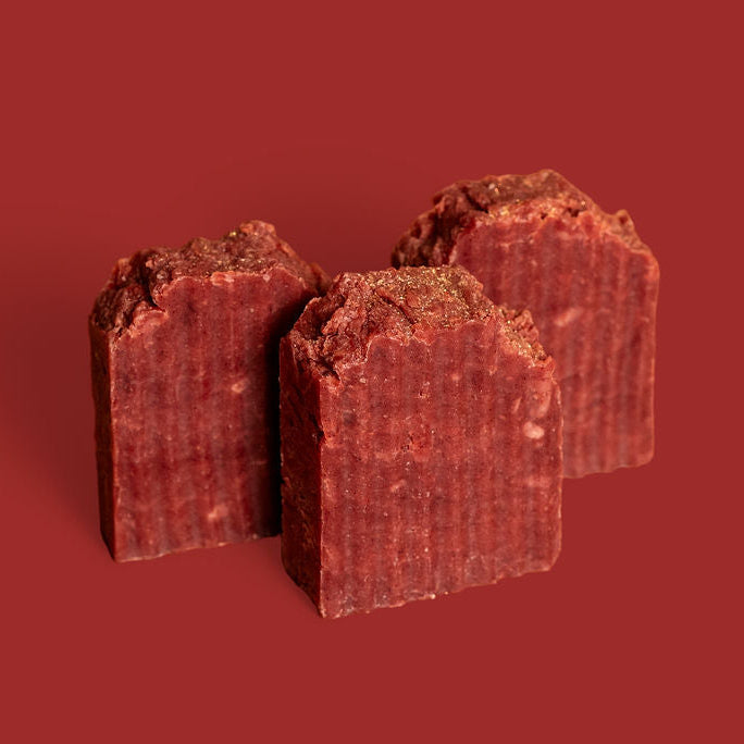 Three pieces of red soap on a red background