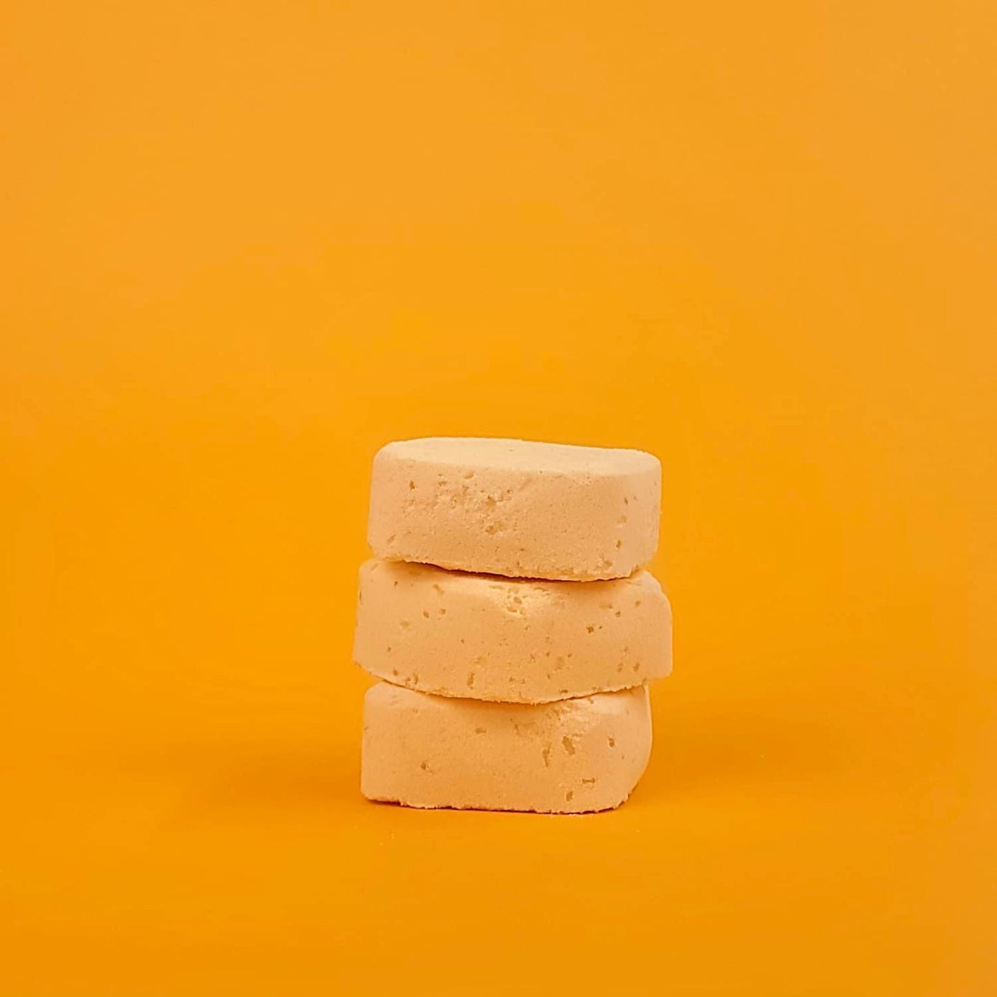 Stack of three beige soap bars on a yellow background