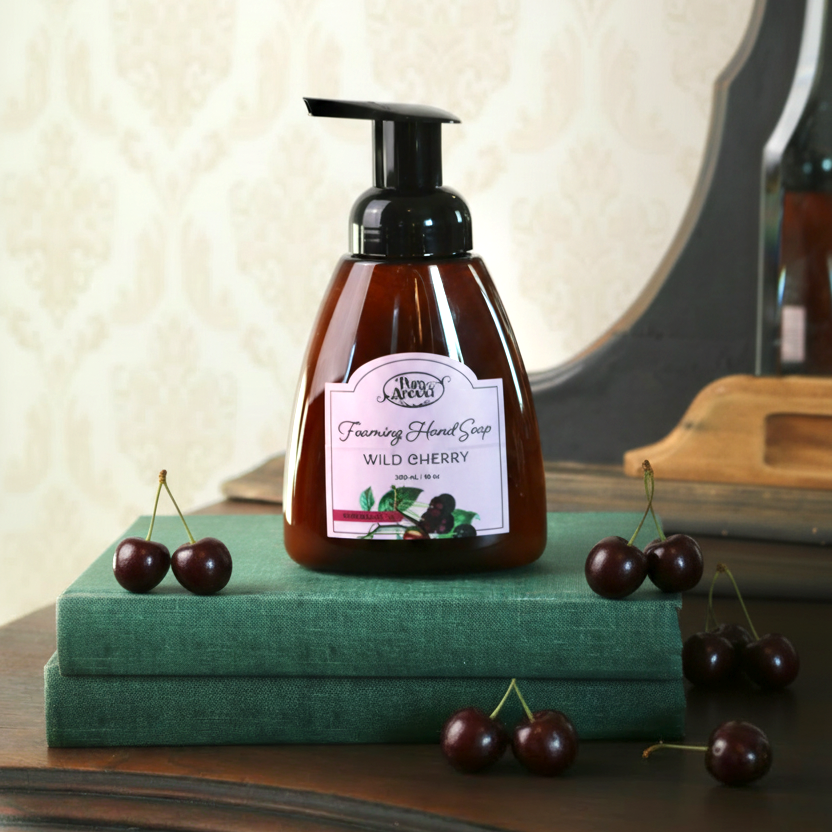 Hand soap bottle with cherry design on a green book, surrounded by cherries.