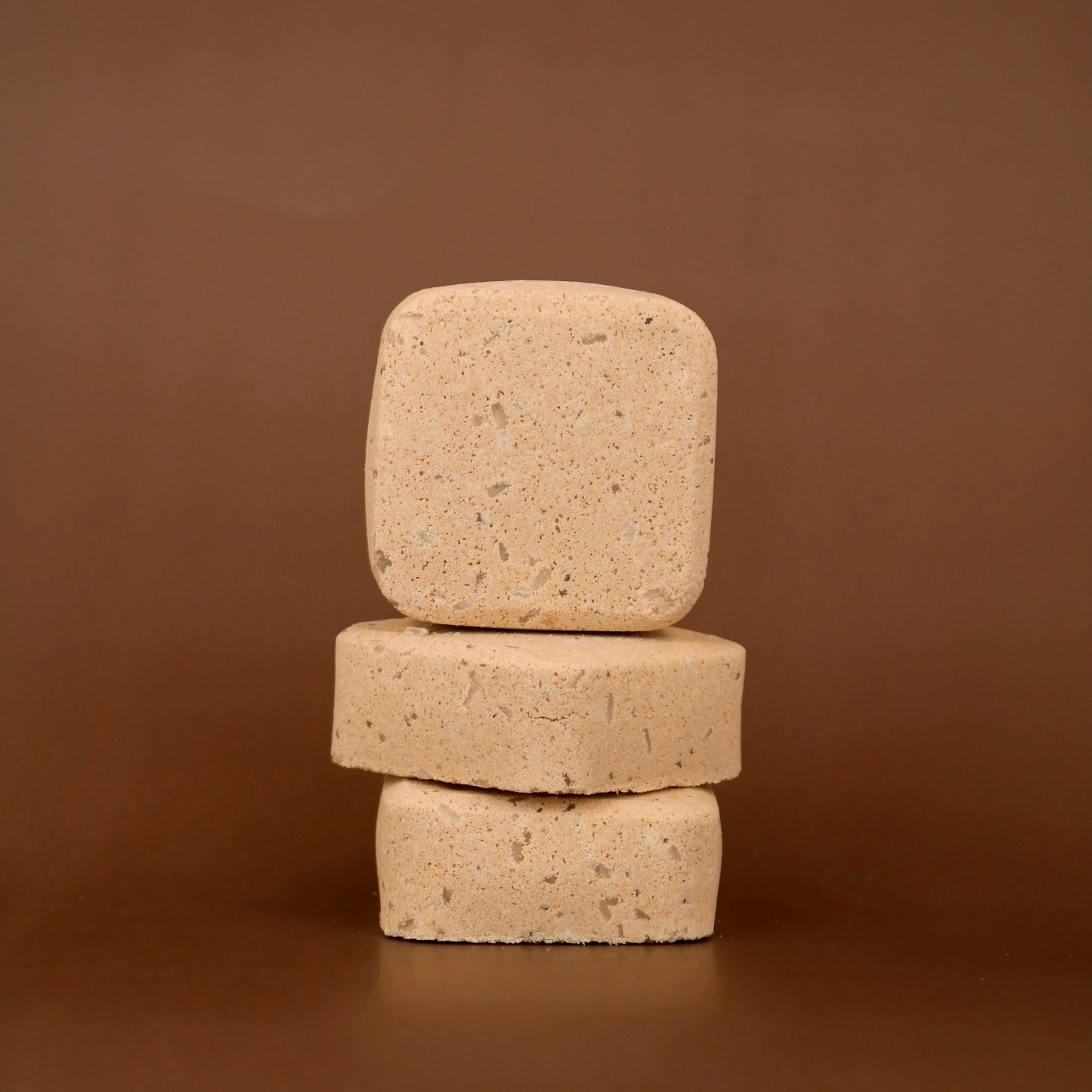 Three stacked root beer scented bath bomb squares on a brown background