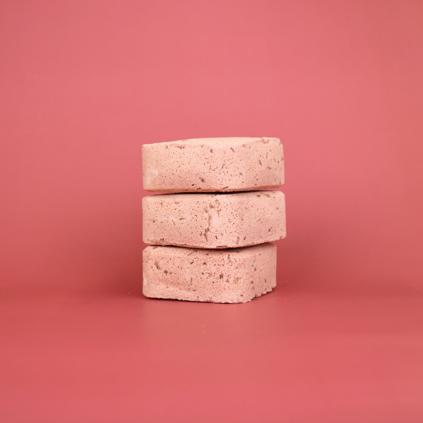 Stack of three beige stones on a pink background