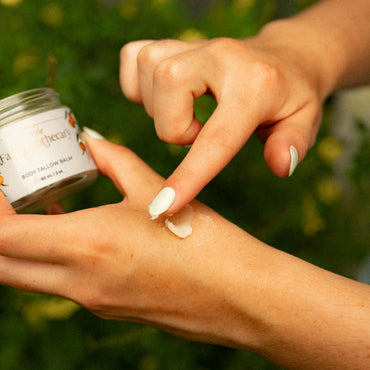 Person applying tallow to their hand with a jar of tallow in the background