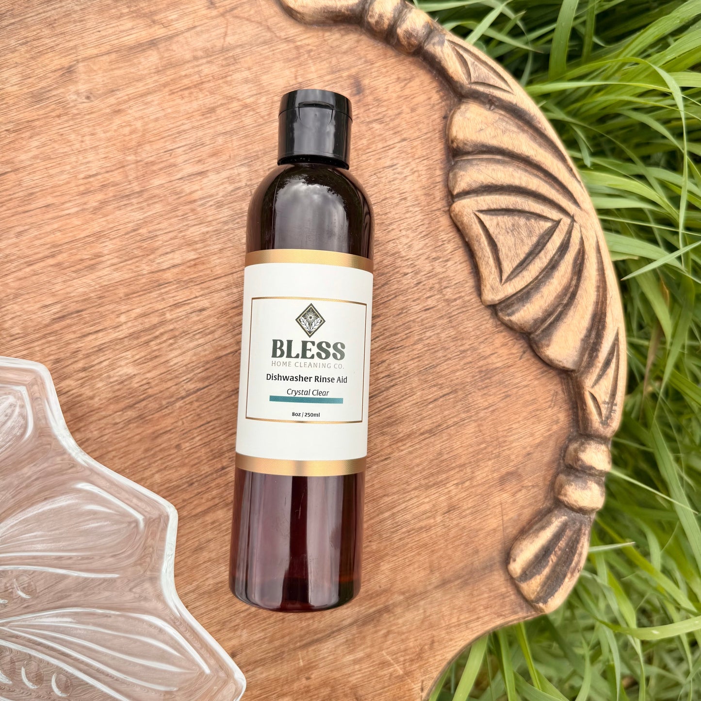 Bottle of 'Bless' oil on a wooden board with grass in the background
