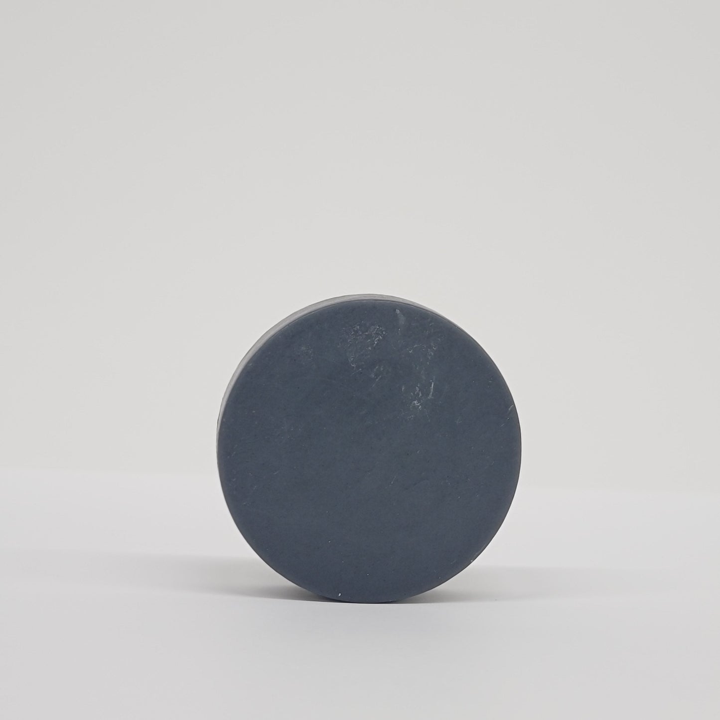 Round black puck soap on a white background