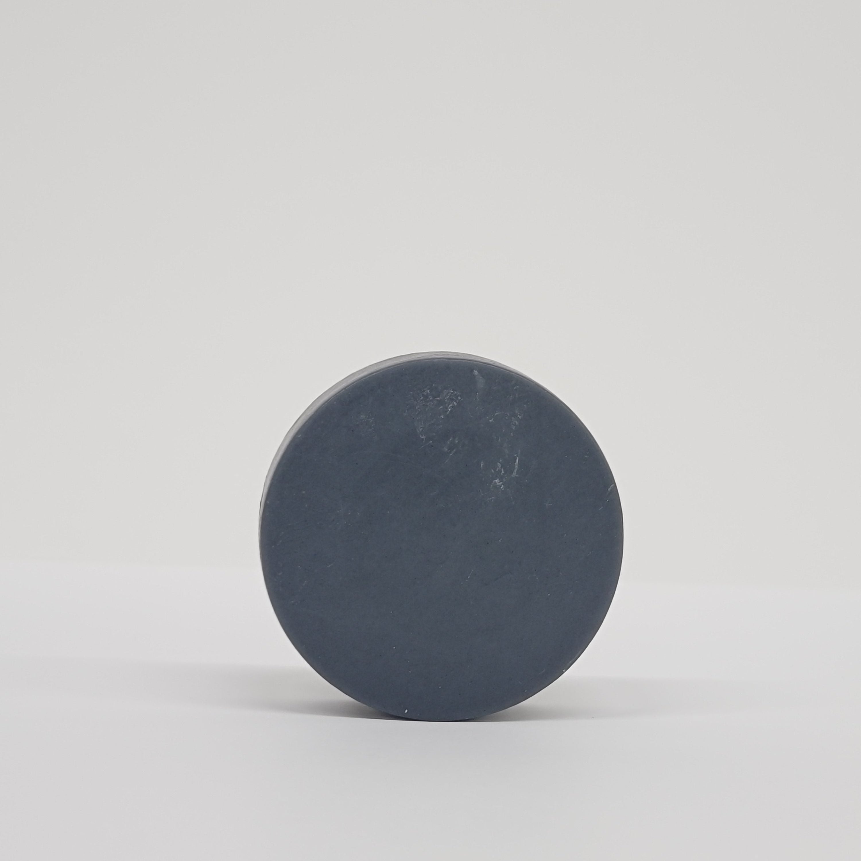 Round black puck soap on a white background