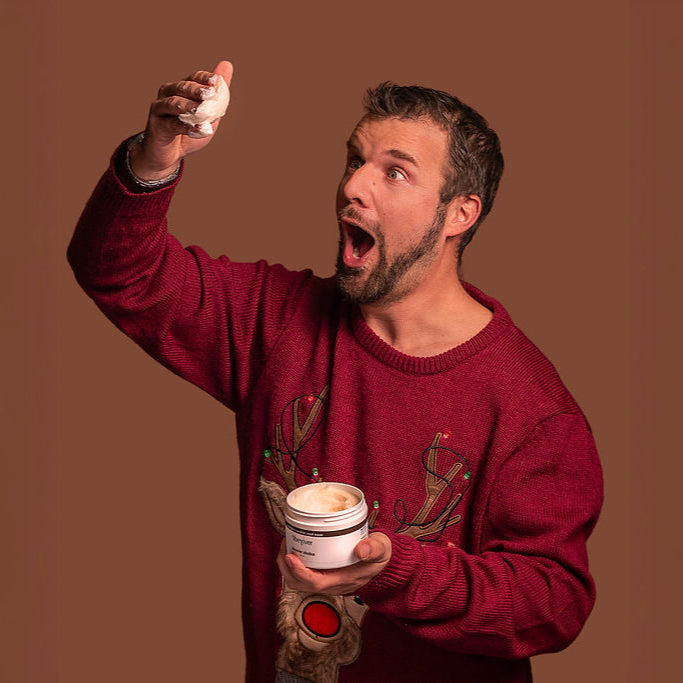 Man in red sweater holding a small container with a brown background