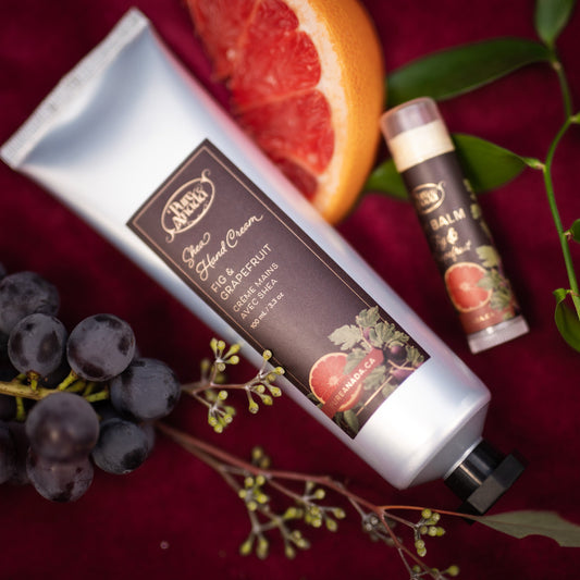 Hand cream and lip balm with grapefruit and grape elements on a red background