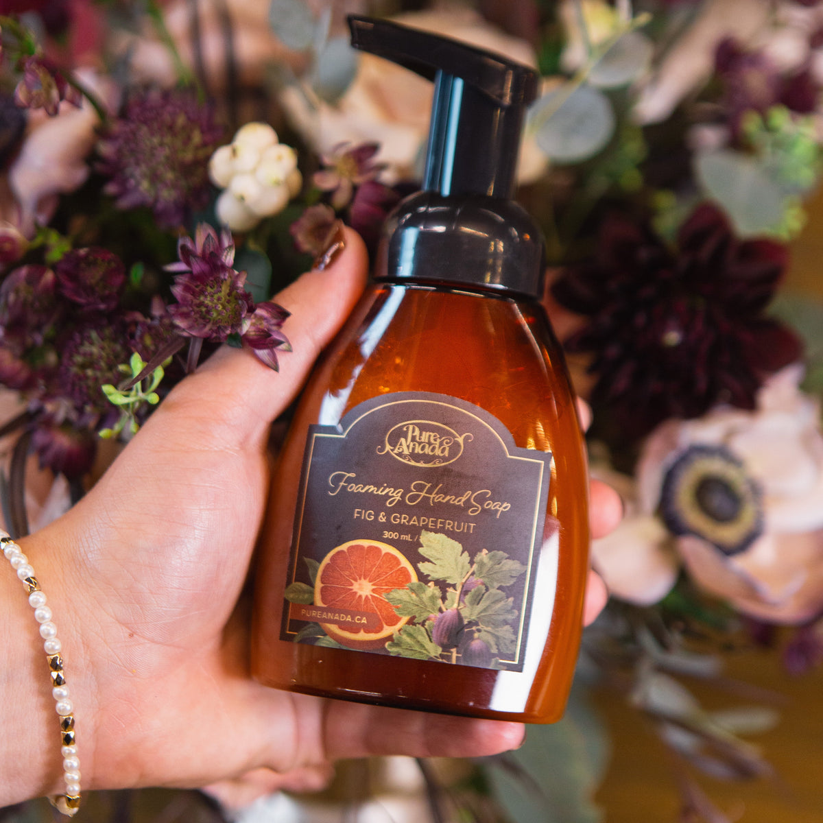 Hand holding a bottle of soap with a floral background