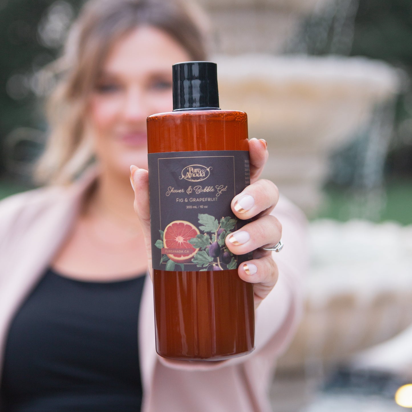 Woman holding a bottle of Johnson's body wash with a fountain in the background