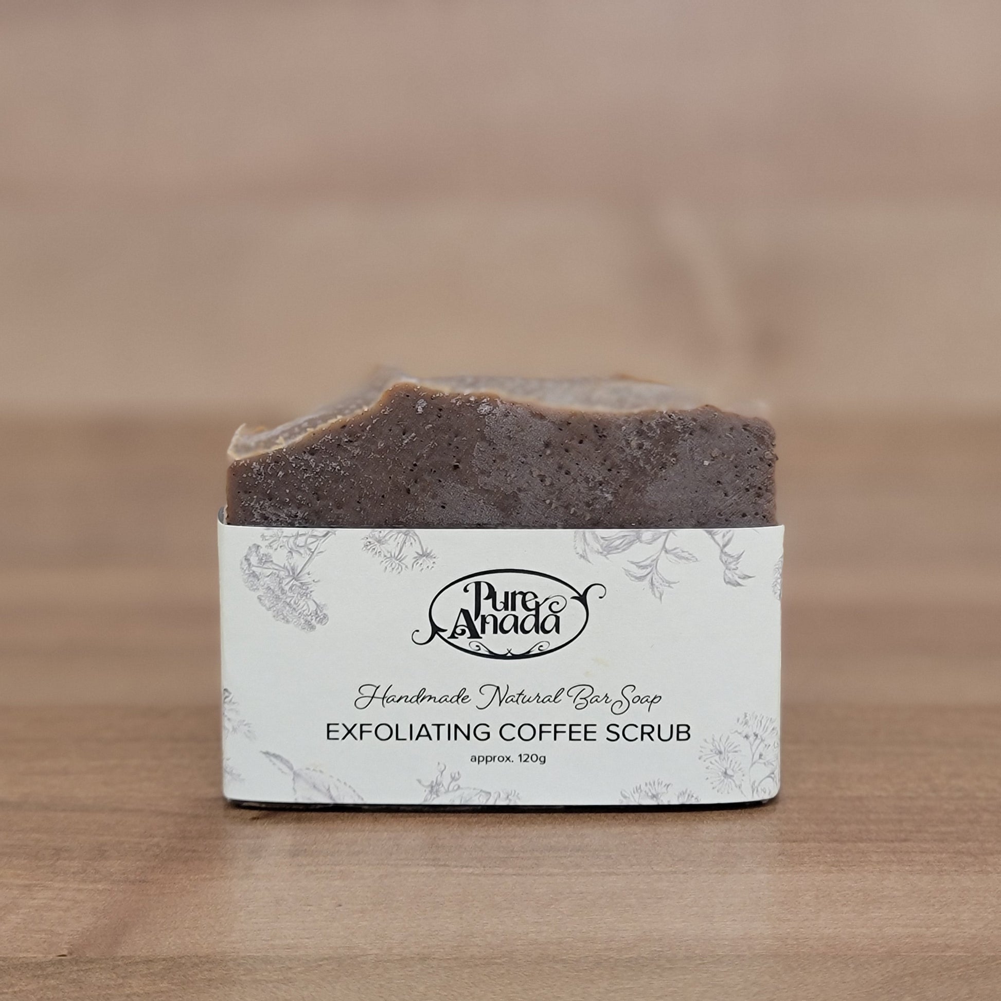 Exfoliating coffee scrub bar with a Pure Anada label on a wooden surface