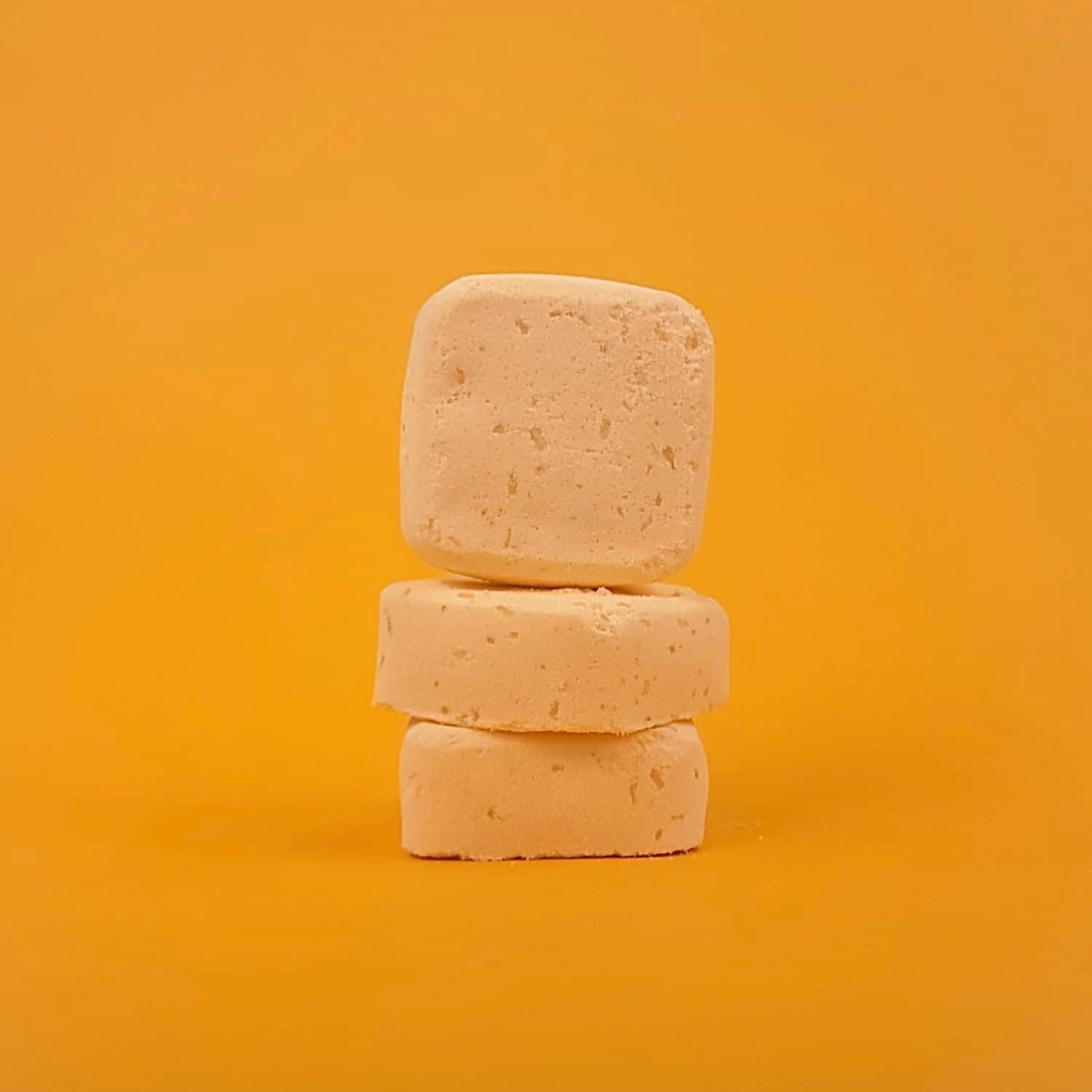 Three stacked soap bars on a yellow background