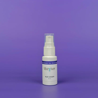 White bottle of eye cream with a blue label on a purple background