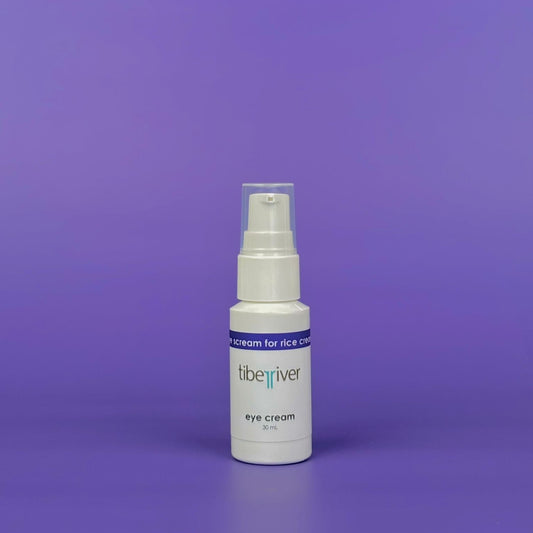 White bottle of eye cream with a blue label on a purple background