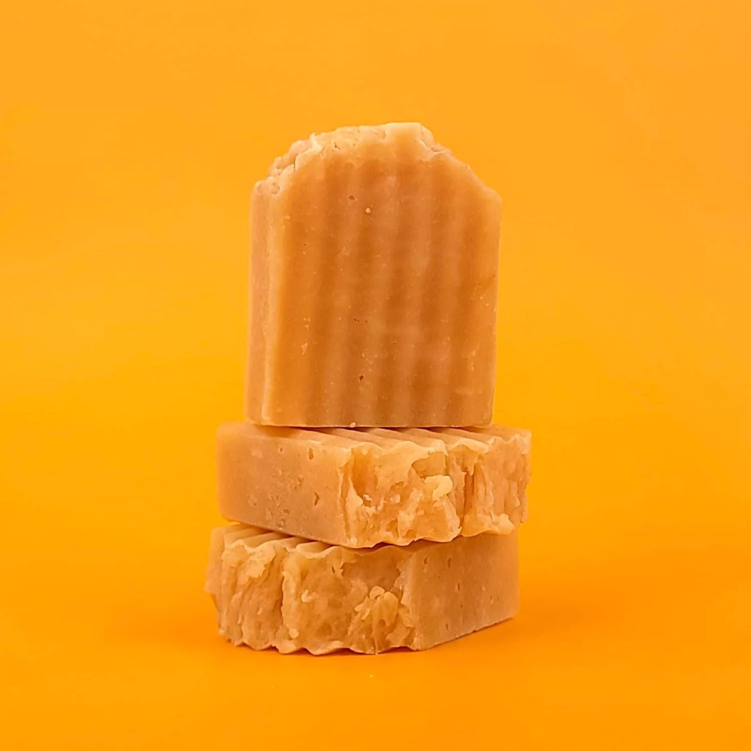 Three bars of brown soap stacked on an orange background