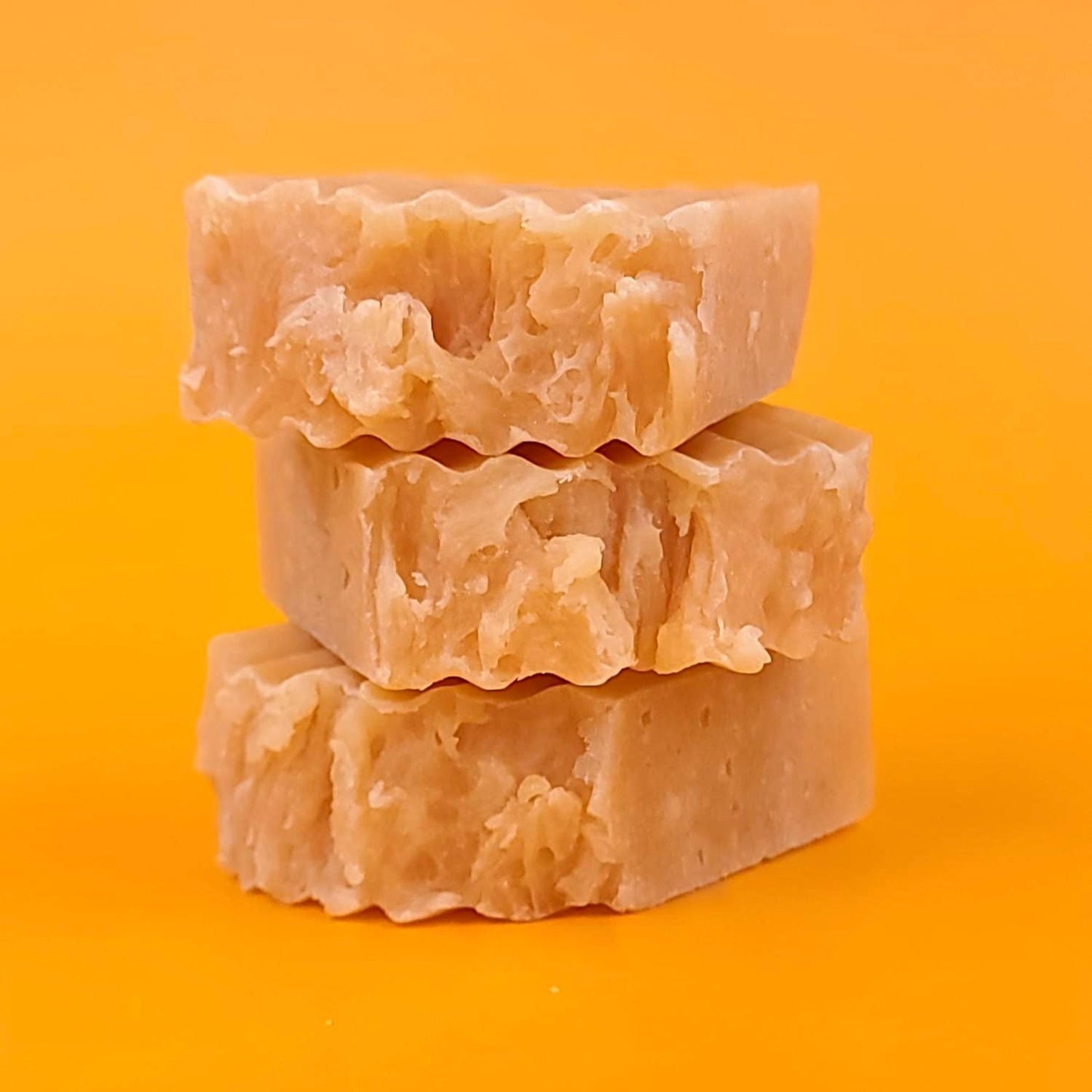 Three bars of soap stacked on an orange background
