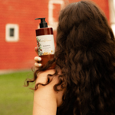 Person holding a bottle of shampoo with a red wall in the background